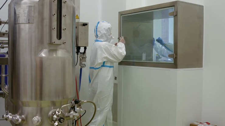 Scientist in protective suits working on vat