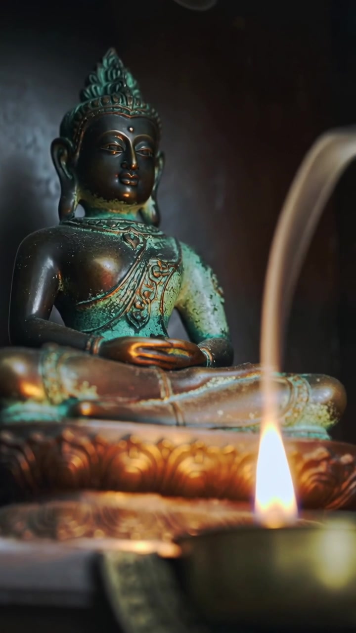 Video verticale: La telecamera si allontana rivelando un Buddha di metallo su un altare, con il fumo di una lampada che crea calma.