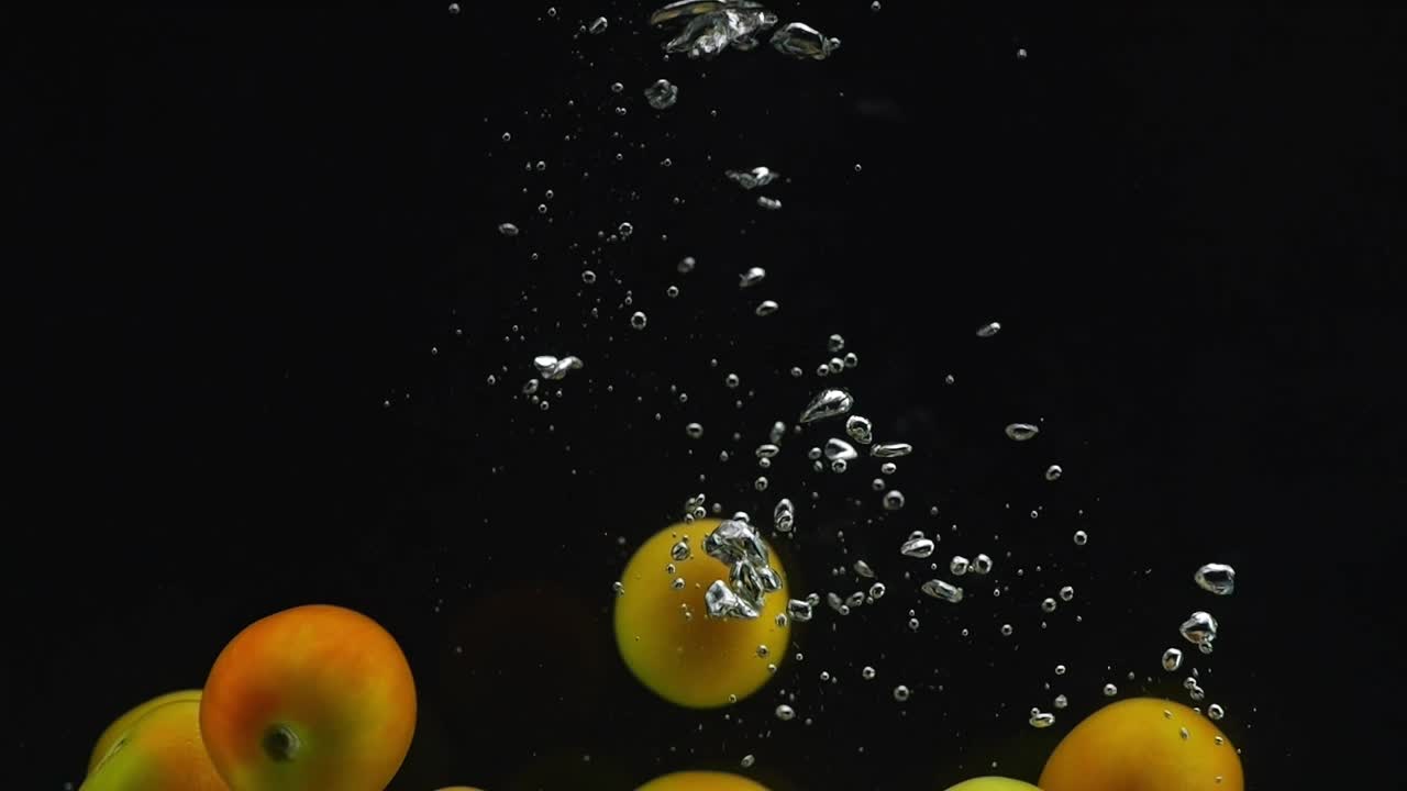 많은 토마토가 검은 바탕에 물에 떨어집니다.