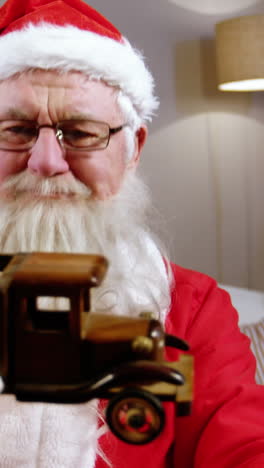 santa claus holding and looking at a toy car