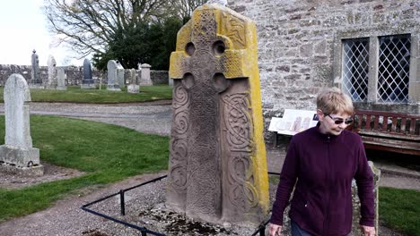 lady examines front face of pictish symbol stone in aberlemno kirkyard