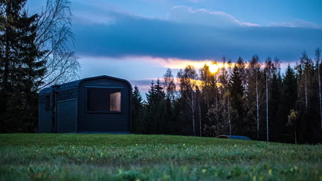 Time-lapse-shot-of-rising-full-moon-at-sky-in-the-evening-in-rural-forest-field-with-wooden-house