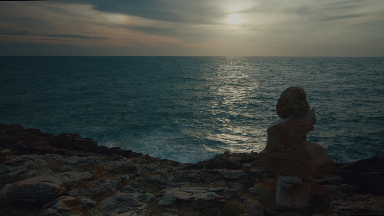 Tramonto sul mare con un cairn di pietre