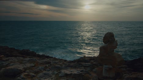 sunset over the sea with a rock cairn