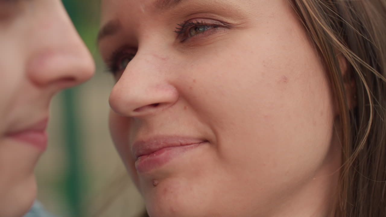 outdoor lovers exchange warm affection, two people share intimate kiss in bright sunlight outside, romantic partners display affectionate gestures amid sunlit scenery and natural surroundings