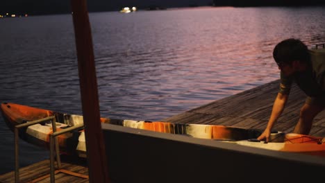 person securing kayak on a dock during evening