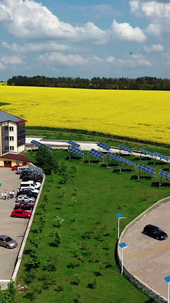 Modern buildings with solar panels on roof on the background of golden field. Solar panels on the roof of private houses, the extraction of electricity by solar panels. Aerial view. Vertical video