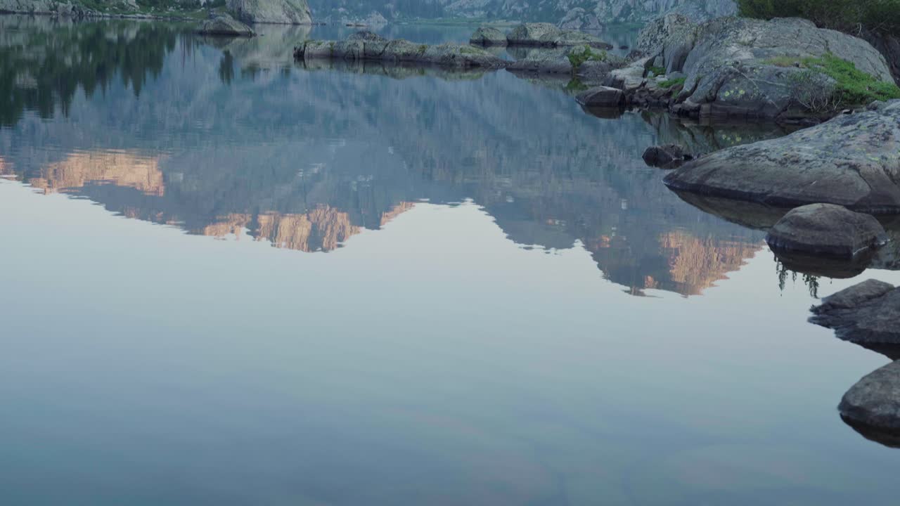 해가 뜨면 차분한 물 위에 반사되는 산꼭대기와 함께 은 알파인 호수에 있는 아침 빛