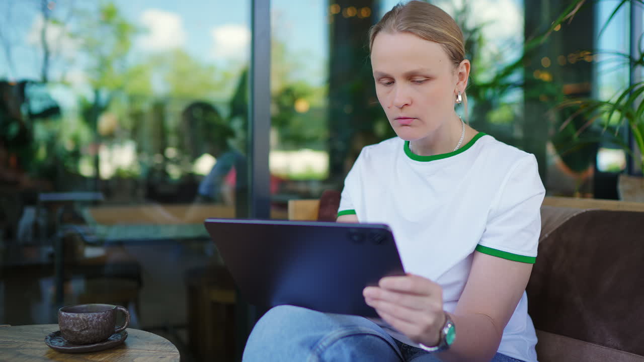 Woman Drinking Coffee and Using Tablet in Cafe