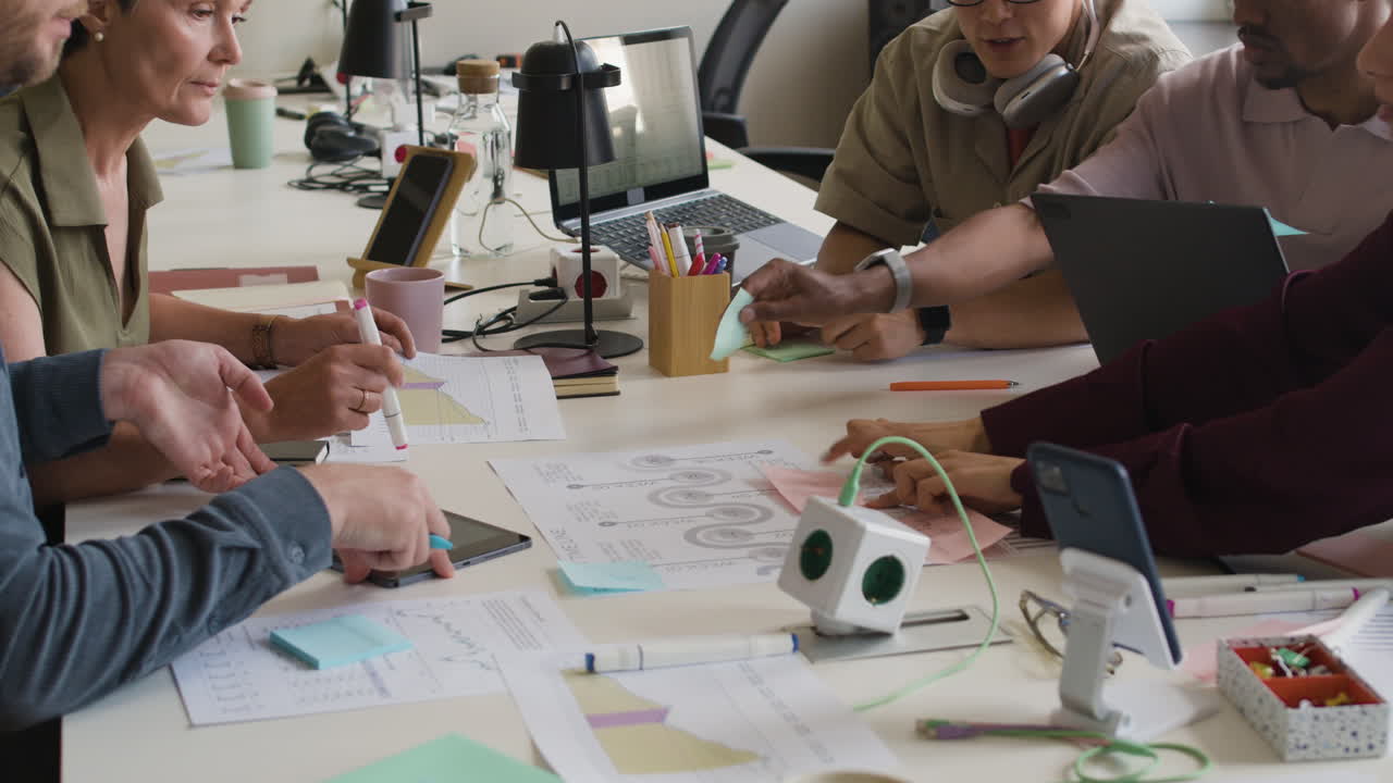 A group of diverse professionals collaborating around a desk in a modern office, engaged in a productive meeting.