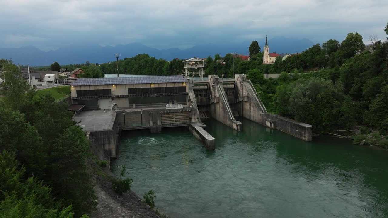 Direct front view of the Mavčiče hydroelectric power plant on the Sava River, showcasing renewable energy infrastructure in a serene Slovenian riverside.