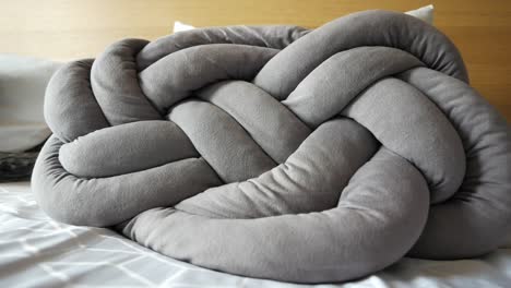 almohada anudada gris en la cama