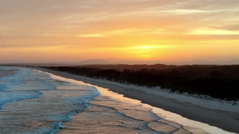 Das-Frühe-Licht-Der-Morgendämmerung-Taucht-Den-Strand-In-Warme-Farbtöne,-Sanfte-Wellen-Streicheln-Das-Ufer