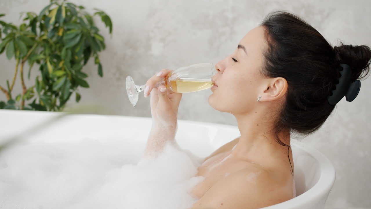 Woman enjoying champagne in a bubble bath