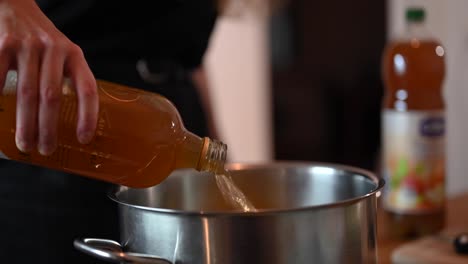 una toma estacionaria de la mano de una mujer mientras vierte el jugo de manzana en una olla de acero inoxidable