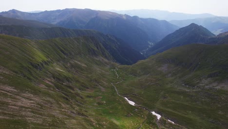 mountain valley with a river cutting through, green slopes and distant peaks, shot in daylight