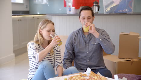 coppia che celebra il trasferimento in una nuova casa con la pizza