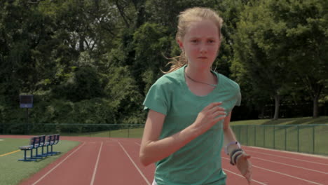 Teen-girl-athlete-on-a-running-track-sprints-past-the-camera-in-slow-motion