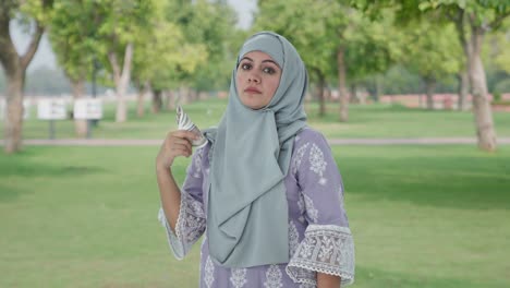 serious muslim woman money as fan in park