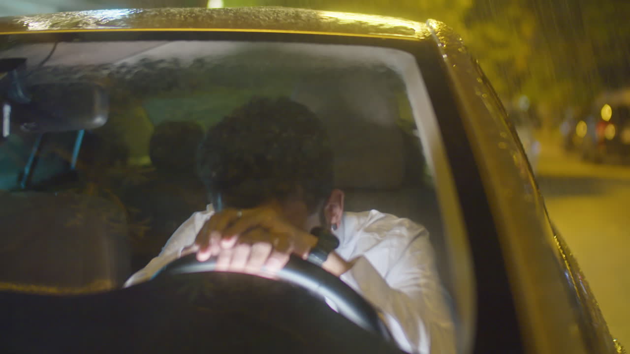 Tired Businessman Sitting in Car at Rainy Night