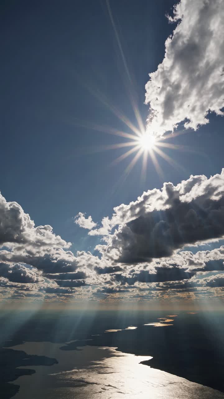 Aerial video shot captures dramatic clouds with sun rays over a shimmering sea, creating a serene