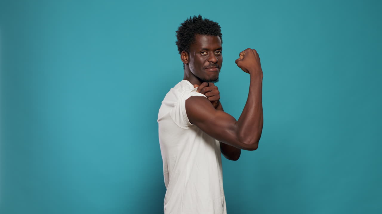 Athletic person flexing biceps muscles on camera in studio