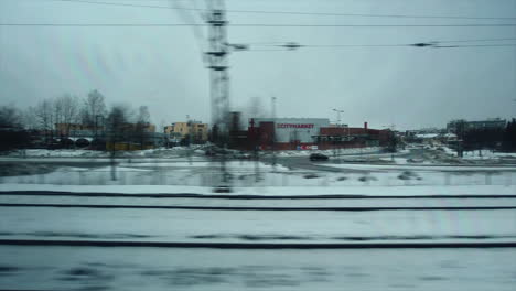 pov desde la ventana: el tren atraviesa el suburbio de la ciudad en un día de invierno nevado