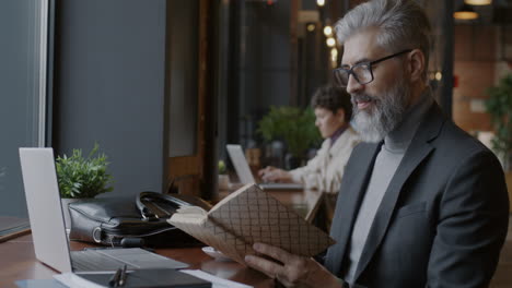 mature businessman reading in a cafe