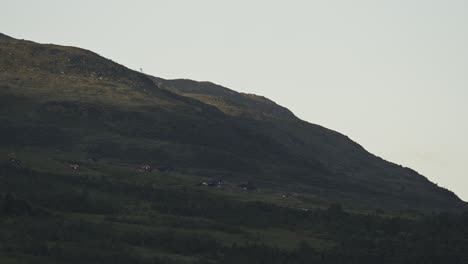 Tag-Nacht-Zeitraffer-Von-Freizeitheimen-In-Den-Bergen-In-Revhaugen-Bei-Aarmot-In-Myrkdalen,-Norwegen---Wolken-Ziehen-Vorbei-Und-Vieh-Bewegt-Sich-Auf-Der-Wiese,-Während-Es-Dunkel-Wird