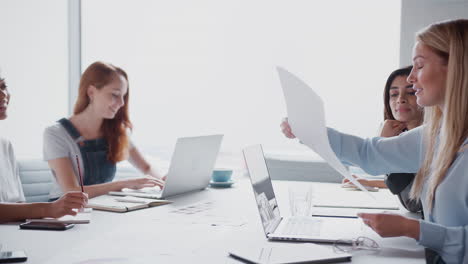 Ein-Team-Junger-Geschäftsfrauen-Trifft-Sich-Am-Tisch-Und-Bespricht-Dokumente-Oder-Pläne-In-Einem-Modernen-Arbeitsbereich