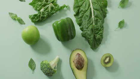 video de aguacate fresco, brócoli, pimienta verde, manzana y hojas verdes sobre un fondo verde