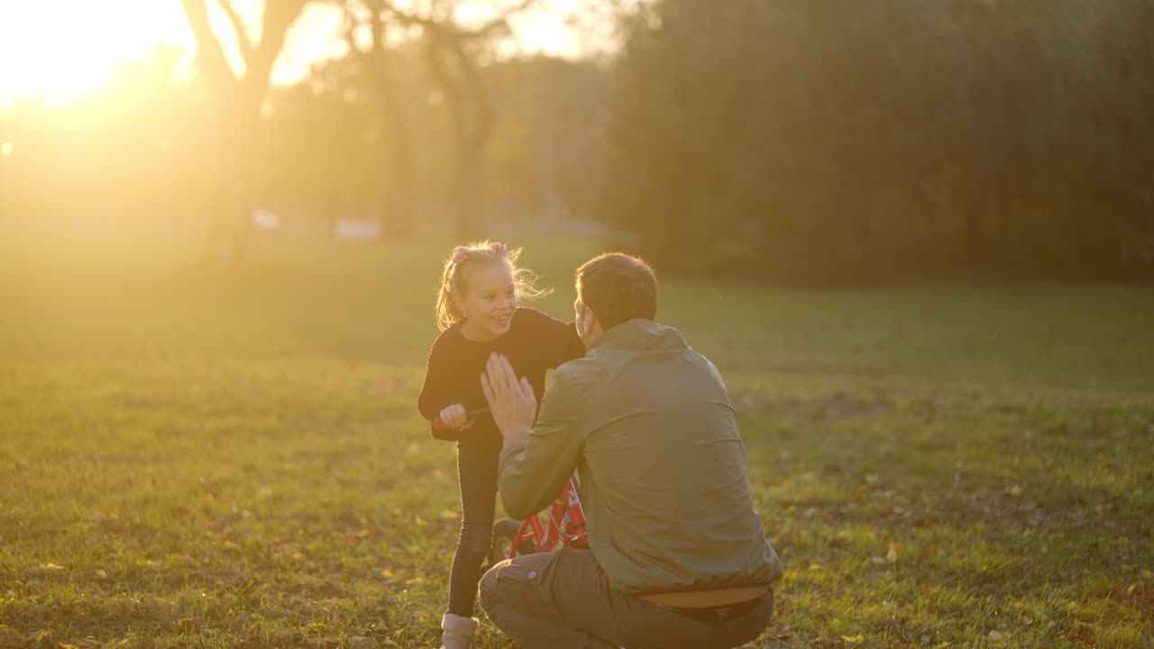 Father teaching his daughter to ride a bike at sunset