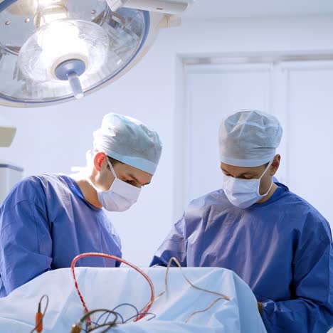 teamwork of surgeons in the operating room. medical specialists in uniform and masks performing a surgery under the modern medical lamp in the hospital.