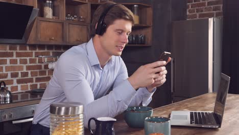 hombre sentado en la mesa con un cuenco y una computadora portátil.