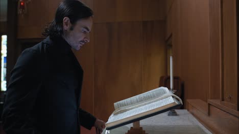 solemn looking christian man in church reading a bible with closeup of pages