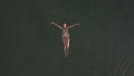 Woman-swimming-on-back-in-the-sea-aerial