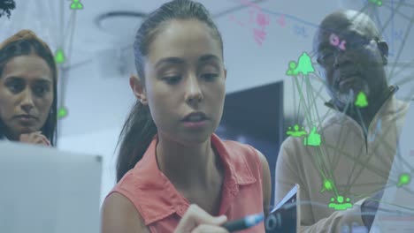 Animation-of-globes-of-digital-icons-spinning-over-biracial-woman-writing-on-glass-board-at-office