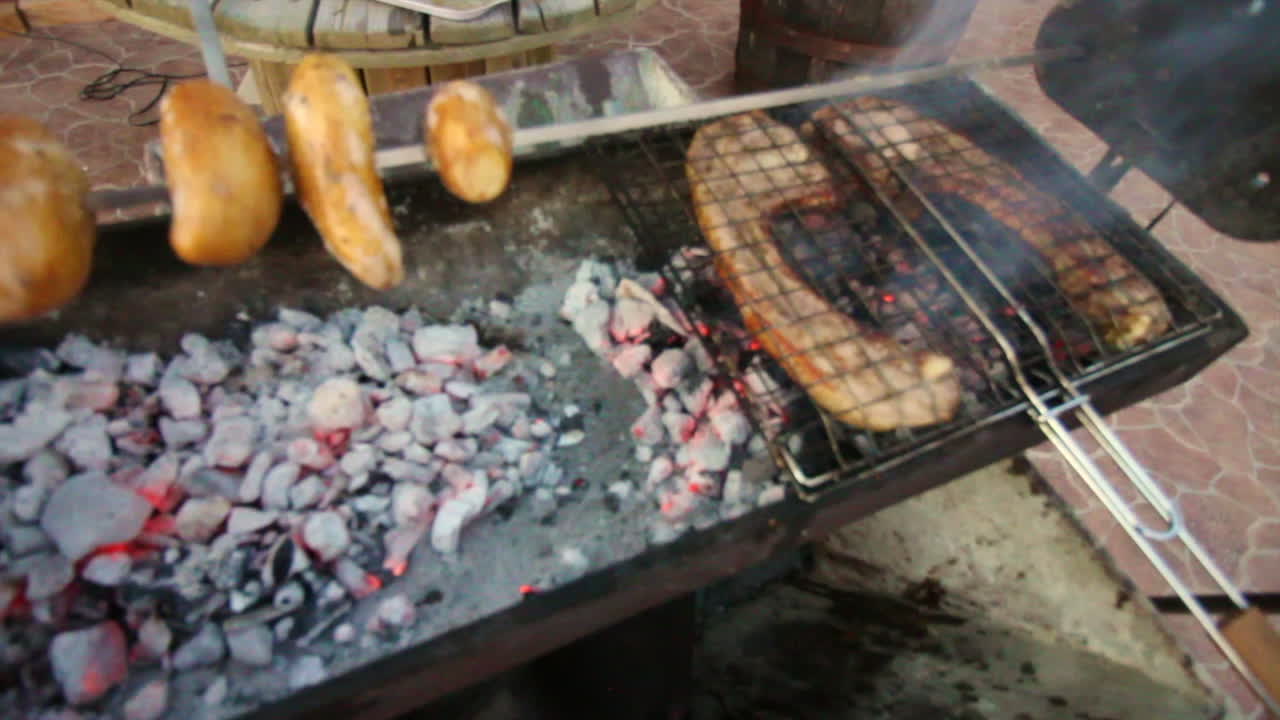 Grilling meat and potatoes on a charcoal barbecue