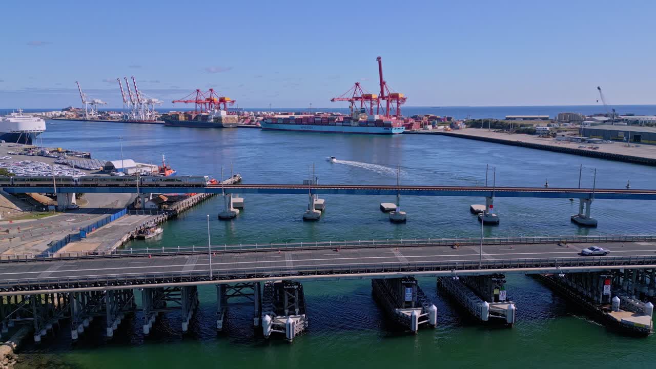 el tráfico de trenes y automóviles cruza el puente del río swan con el puerto de carga en el fondo en fremantle, australia occidental