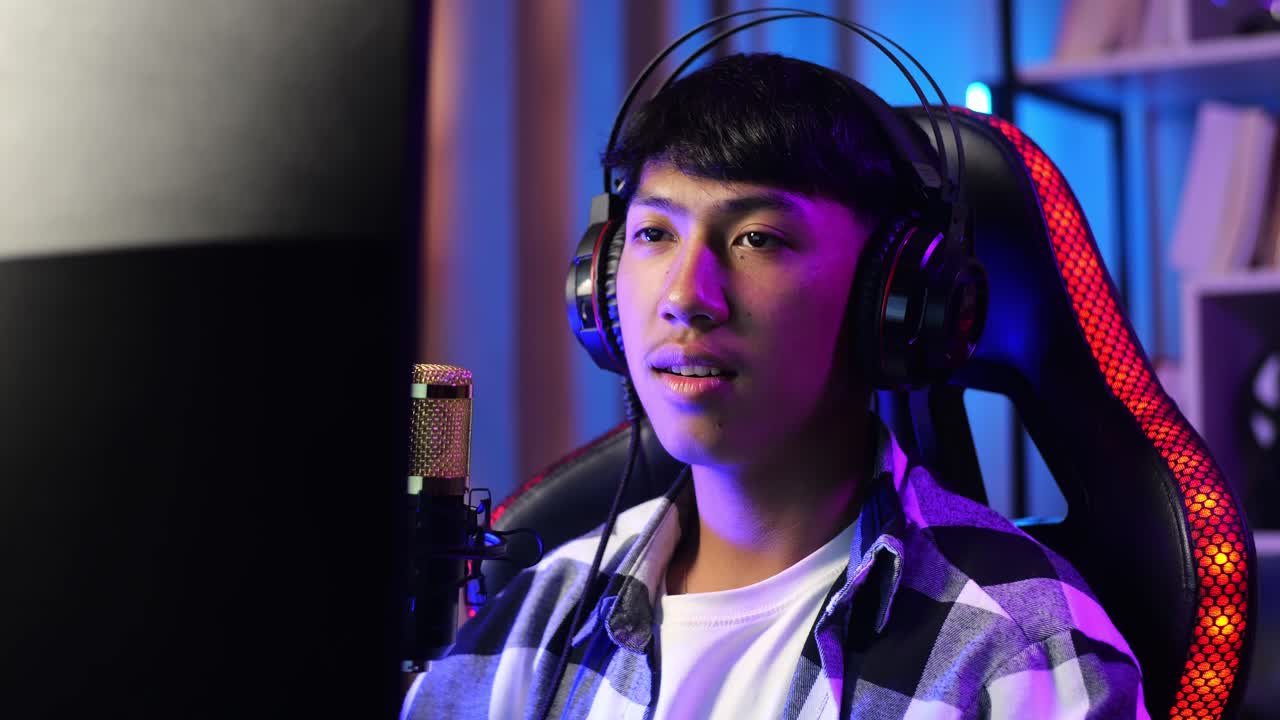 primer plano de un niño asiático con dolor de espalda mientras juega un juego a través de la red en una computadora personal. videojuego de transmisión en vivo, escritorio iluminado por luz de tira led rgb