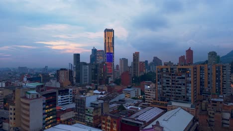 ascending aerial view of the colpatria tower illuminated with the colors of the colombian flag with the sunset in the background.