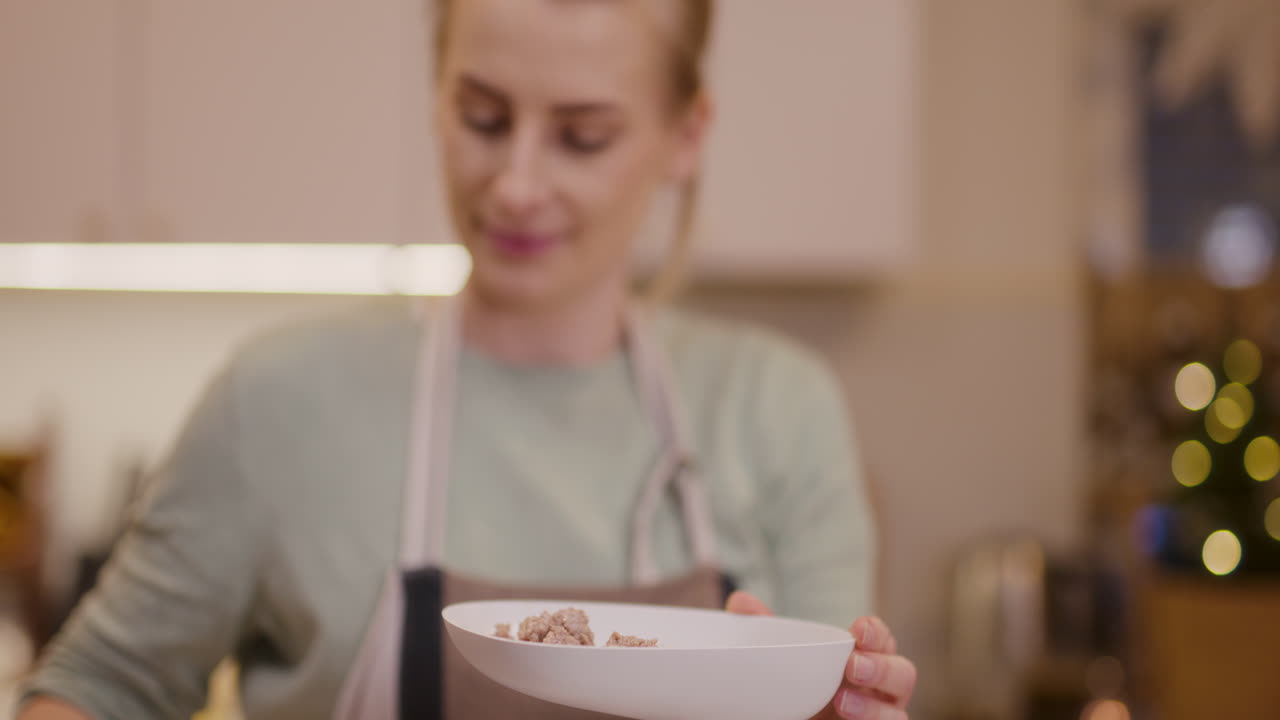 mujer pone carne en el molinillo de carne y prepara platos de vacaciones