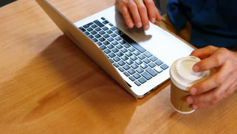 hombre de negocios tomando una taza de café mientras usa una computadora portátil