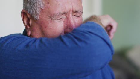 Portrait-of-senior-caucasian-man-coughing-or-sneezing-into-his-arm