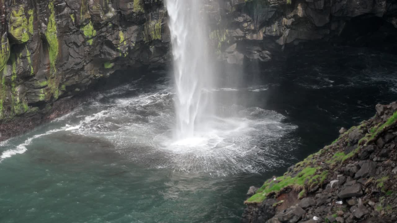 A stunning view of Múlafossur waterfall crashing into the ocean below, serene and wild