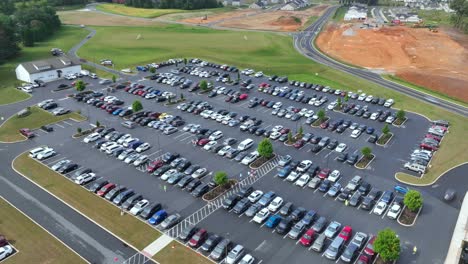 cars and people entering and exiting large asphalt parking lot in usa