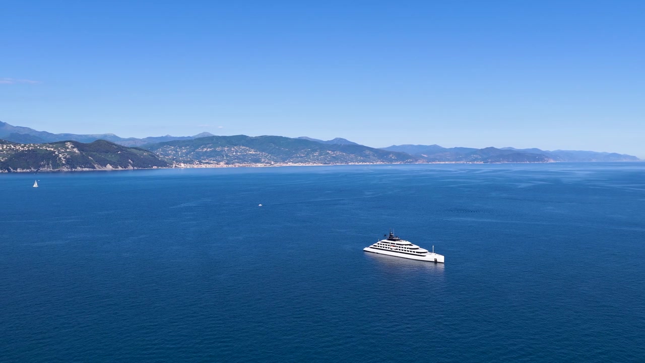 Bredt luftperspektiv af et luksusfartøj, der navigerer i Middelhavet under klar blå himmel.