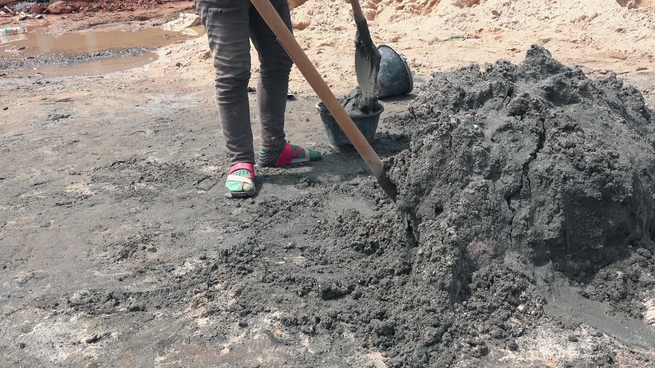 작업자가 양동이에 시멘트를 삽질하고 있습니다.