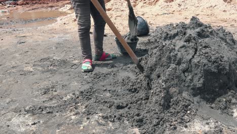 worker shovelling cement into a bucket