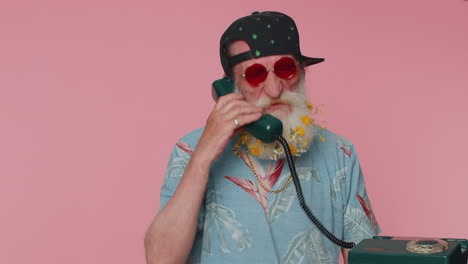 Crazy-stylish-senior-old-man-talking-on-wired-vintage-telephone-of-80s,-fooling,-making-silly-faces